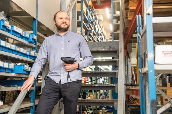 Raskoneen IT Team Manager Maxim Demin seisoo varaston portailla Panasonic-päätelaite kädessään Kuva Paula Ojansuu