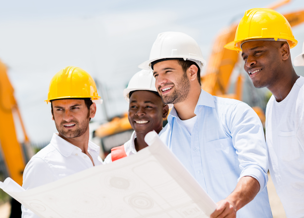 Engineers working on a building site holding a blueprints