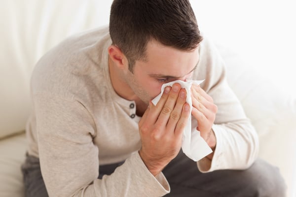 mies niistää nenää sohvalla istuen Kuva: Shutterstock