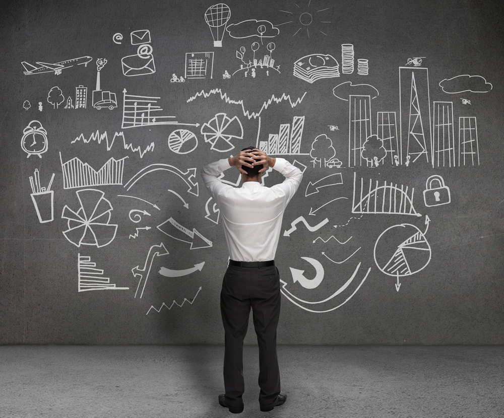 Stressed businessman looking at drawings of charts and sketches on a wall Credit: Shutterstock