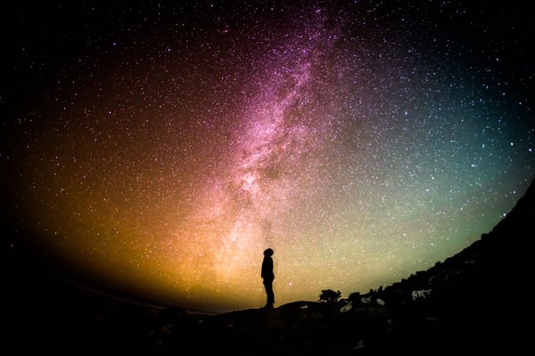 ihminen tuijottaa värikkäälle tähtitaivaalle Credit: Greg Rakozy Unsplash