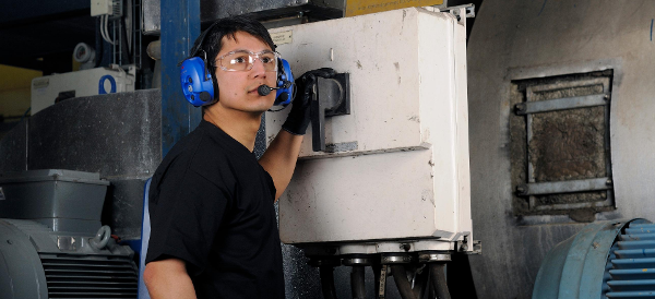 Mies käyttää hallintalaitteita teollisuusympäristössä viestintäkuulosuojaimet päässään Kuva: Peltor