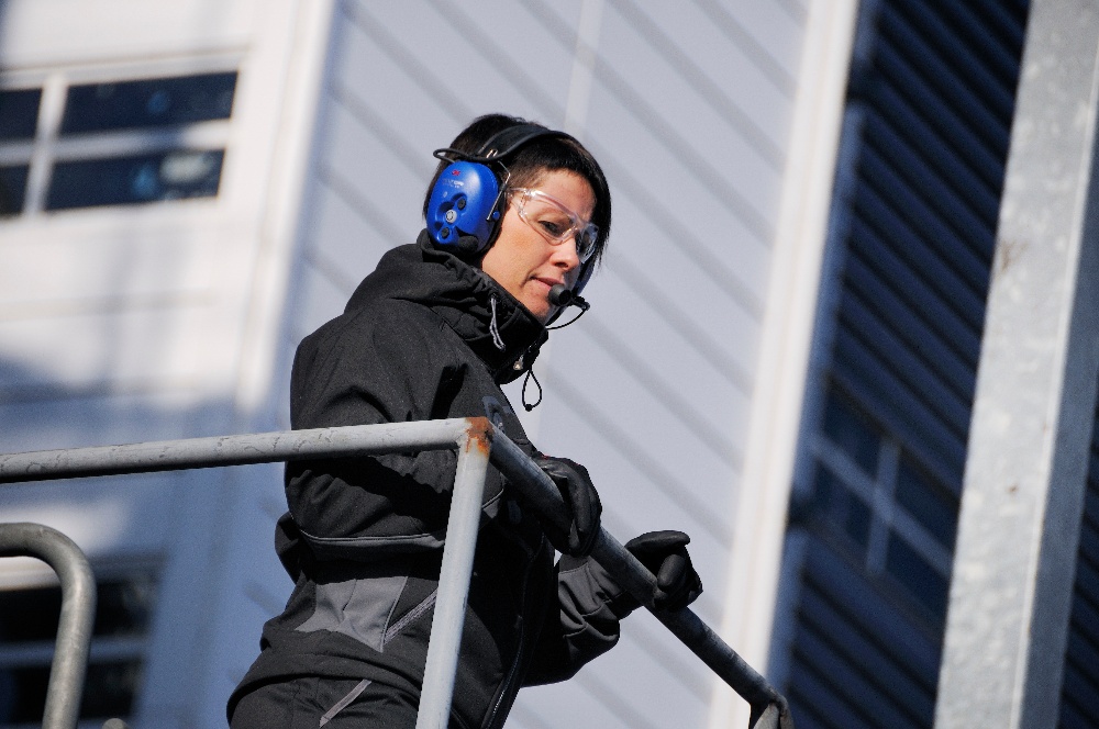 nainen valvoo tehdasympäristöä viestintäkuulosuojaimet päässään Kuva: Peltor
