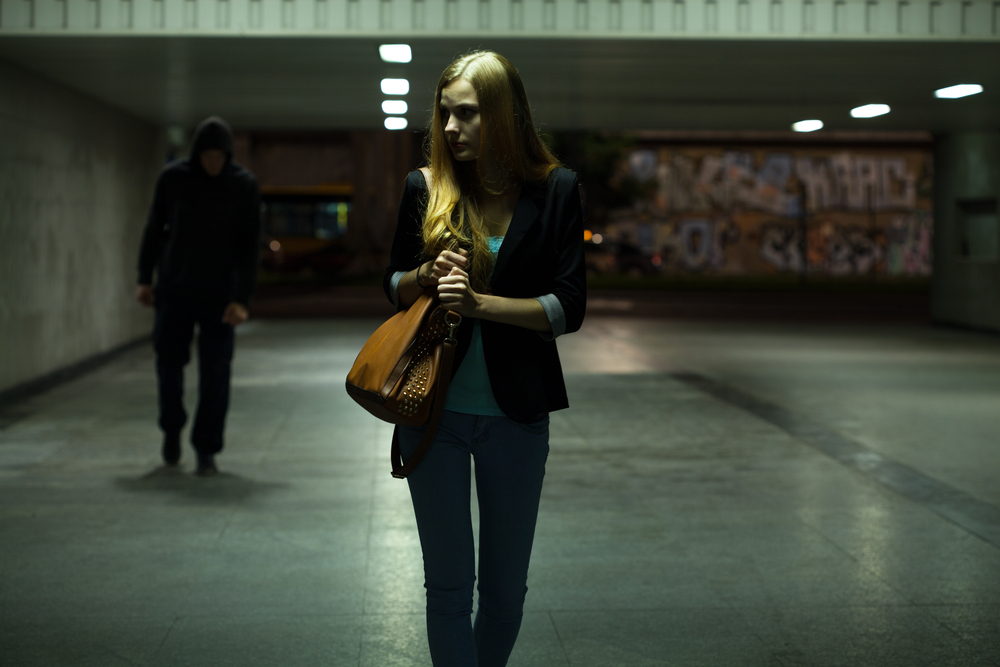henkilö pakenee tummaa hahmoa joka kävelee hänen perässään alikulussa Kuva: Shutterstock